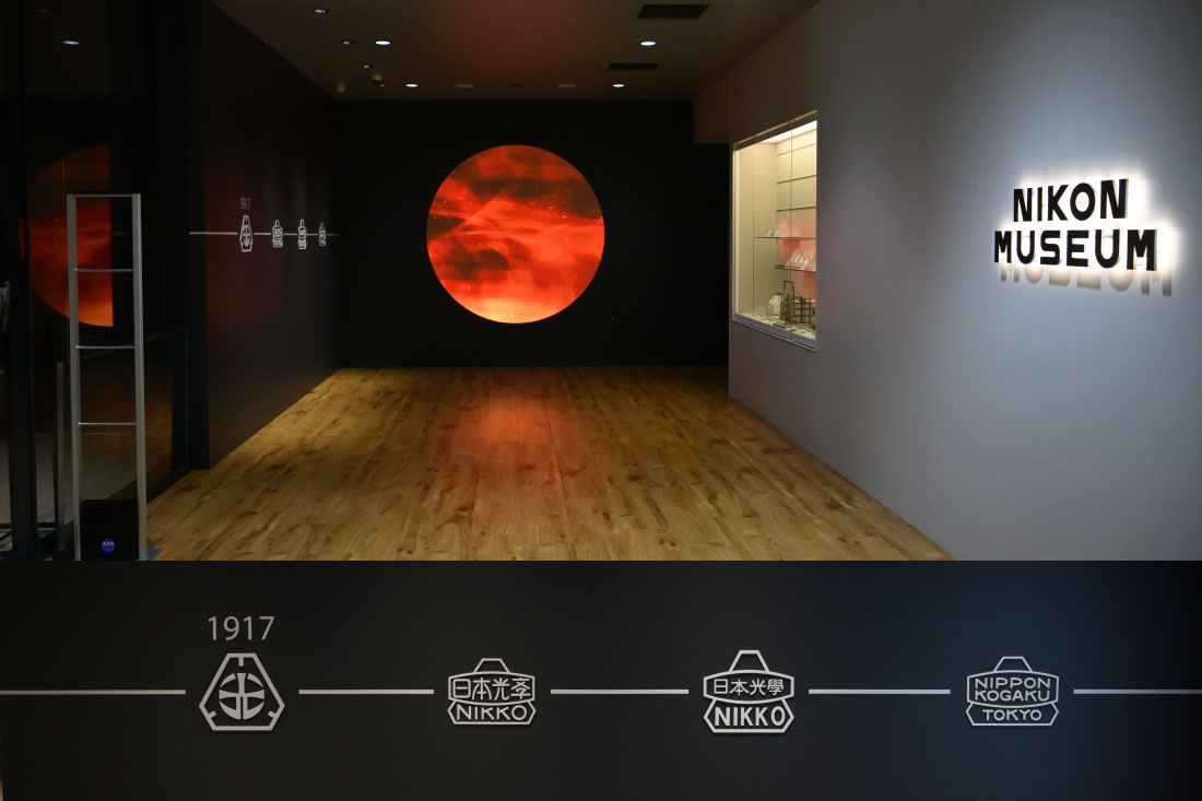 Nikon Museum尼康博物館門口處的陳列裝置透著理工氣質的浪漫，側牆上是LOGO演進史